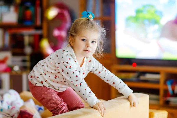 Słodka dziewczynka w piżamie nocnej oglądająca kreskówki lub film w telewizji. Szczęśliwe zdrowe dziecko w domu. — Zdjęcie stockowe