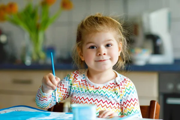 Bonito adorável bebê menina aprendendo pintura com cores de água. Criança pequena desenhando em casa, usando pincéis coloridos. Filha feliz saudável experimentando com cores, água em casa ou no berçário — Fotografia de Stock