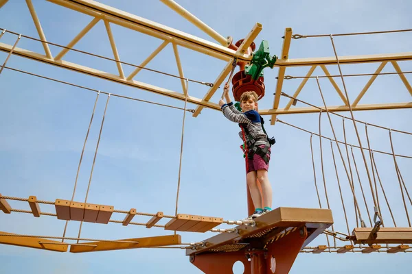 Happy little kid boy climbing on high rope course trail. Active child making adventure and action on family vacations. Challenge for brave kids. — Stockfoto