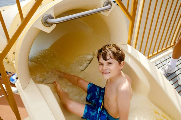 Pequeño niño feliz deslizándose en el tubo de tobogán de agua en el parque del resort. Niño sano divirtiéndose . — Foto de Stock