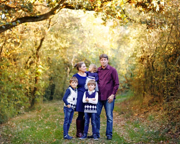 Porträtt av unga föräldrar med tre barn. Mor, far, två barn bröder pojkar och liten söt småbarn syster flicka har roligt tillsammans i höstskogen. Lycklig familj på fem — Stockfoto