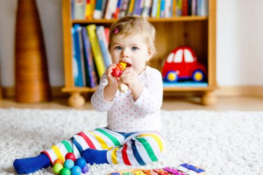 Evde ya da çocuk odasında eğitici oyuncaklarla oynayan sevimli, güzel bir kız bebek. Mutlu sağlıklı çocuk renkli müzik oyuncağıyla eğleniyor ksilofon çocuk farklı beceriler öğreniyor