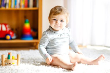 Eğitici oyuncaklarla oynayan sevimli bir kız bebek. Mutlu sağlıklı çocuk evde renkli tahta oyuncaklarla eğleniyor. Doğa oyuncağı olan çocuklar için erken gelişim.