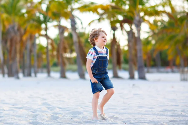 可爱的活泼的小男孩在岛上的热带海滩上玩得很开心。快乐可爱的孩子在温暖的阳光下，在棕榈和海洋边放松、玩耍、享受、跑步和跳跃。积极的家庭假期 — 图库照片