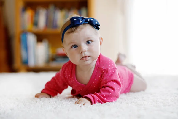 Babymeisje met blauwe ogen liggend op buik. Crèche voor kinderen. Textiel en beddengoed voor kinderen. Gelukkig leuk nieuw geboren meisje. kind met beugel. — Stockfoto