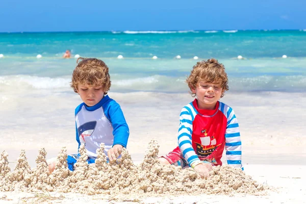 Twee kinderen weinig plezier met het bouwen van een zandkasteel op tropisch strand van Malediven jongens. kinderen samenspelen op hun vakanties Twins, Happy broers lachen en glimlachen. — Stockfoto