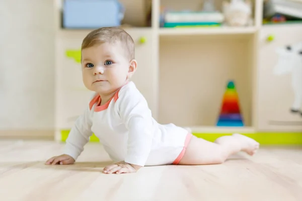 Cute baby girl learning crawling and sitting in children room at home. New born child, little girl lying on belly. Family, new life, childhood, beginning concept — Stock Photo, Image