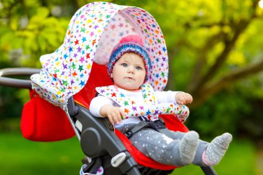 Mavi, sıcacık şapkalı, bebek arabasında ya da bebek arabasında oturan ve annesini bekleyen sağlıklı küçük güzel bir kız bebek. Mavi gözlü mutlu çocuk. Küçük kızım ailesiyle yürüyüşe çıkıyor.