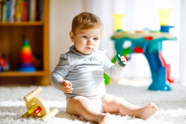 Eğitici oyuncaklarla oynayan güzel bir kız bebek. Mutlu sağlıklı çocuk evde renkli tahta oyuncaklarla eğleniyor. Doğa oyuncağı olan çocuklar için erken gelişim.
