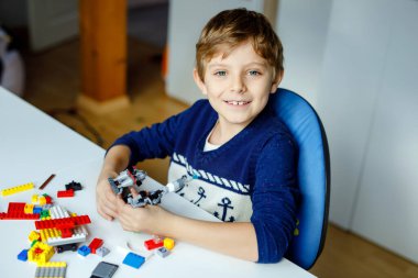 Renkli plastik bloklar çok oynayan küçük sarışın çocuk. Sevimli okul çocuk çocuk bina ve robot oluşturma ile eğlenmek. Yaratıcı eğlence modern teknik ve robotik.