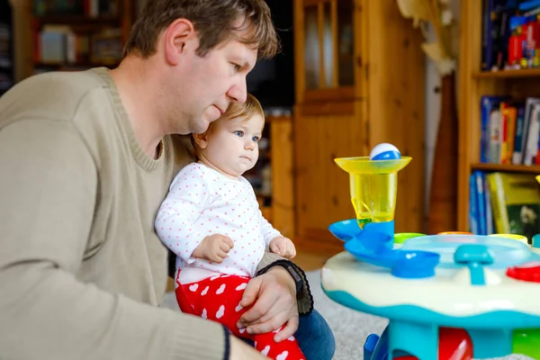 Gelukkig trotse jonge vader plezier met baby dochter, familieportret samen. Papa spelen met babymeisje met educatieve sorter speelgoed met verschillende kleurrijke ballen. Man met klein kind thuis. — Stockfoto