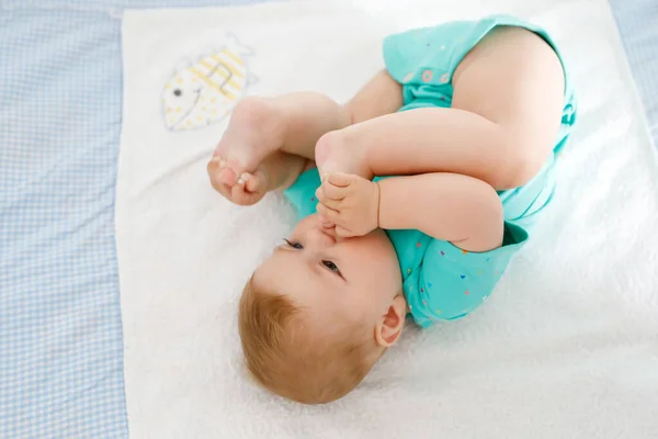 Söt baby med fötter i mun. Bedårande liten flicka sugande fot. — Stockfoto
