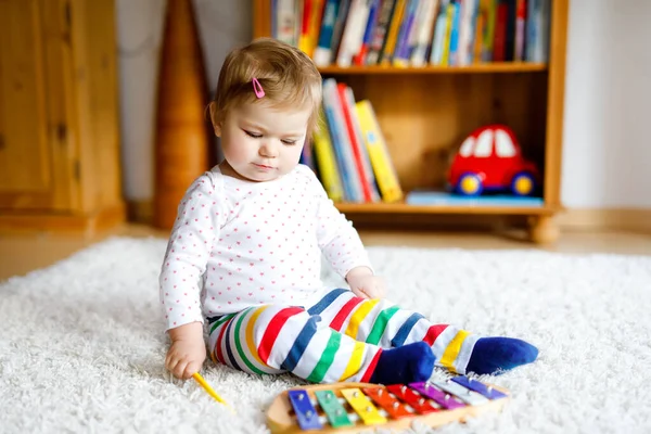 Адекватная симпатичная маленькая девочка, играющая с развивающими игрушками дома или в детском саду. Счастливый здоровый ребенок развлекается с красочной музыкальной игрушкой ксилофон Ребенок учится различным навыкам — стоковое фото