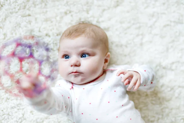 Carino adorabile neonato che gioca con il giocattolo colorato palla su sfondo bianco. Bambino appena nato, bambina che guarda la macchina fotografica. Famiglia, nuova vita, infanzia, concetto iniziale. Baby apprendimento afferrare sonaglio. — Foto Stock