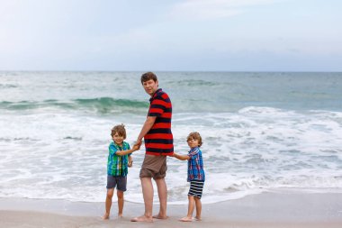 İki mutlu küçük çocuk okyanus sahilinde durup fırtınalı bir günde ufka bakıyorlar. Aile, baba ve tatlı oğullar tatil yapıyor, hayal kuruyor ve yazın tadını çıkarıyorlar.