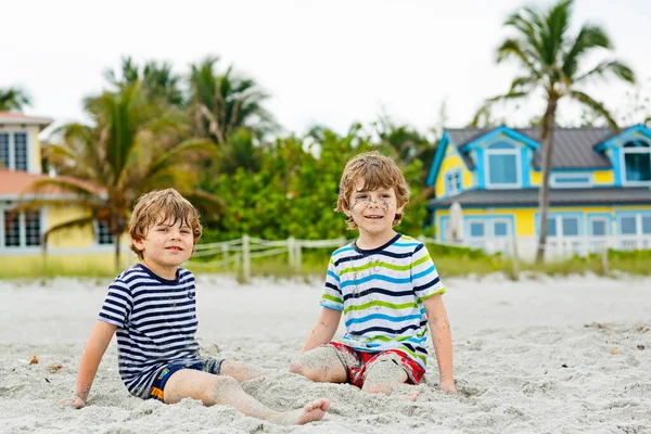 Dwa małe dzieci chłopcy zabawy z budynku zamek z piasku na tropikalnej plaży w Miami beach, Floryda dzieci grać razem na wakacje — Zdjęcie stockowe