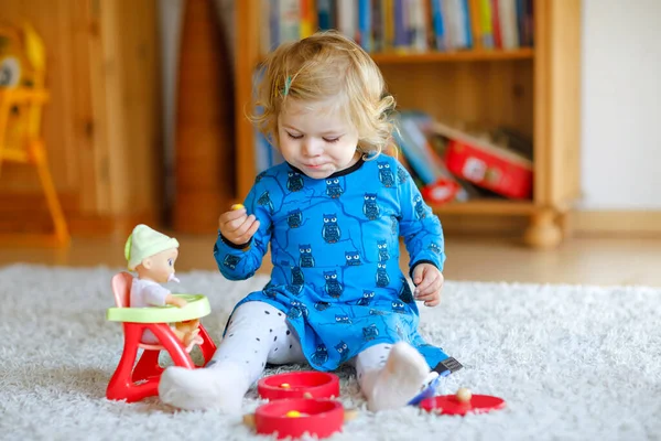 Gadis balita kecil yang manis bermain dengan boneka. Bayi yang sehat bersenang-senang dengan permainan peran, bermain sebagai ibu di rumah atau pembibitan. Putri aktif dengan mainan. — Stok Foto