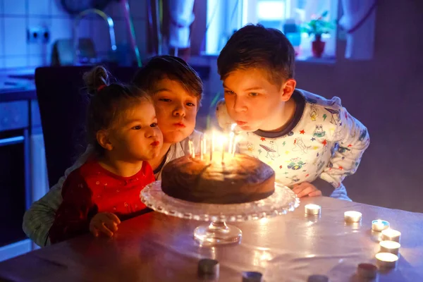 Adorable kid boy celebrating tenth birthday. Baby sister child and two kids boys brothers blowing together candles on cake. Happy healthy family portrait with three children siblings — Stock Photo, Image