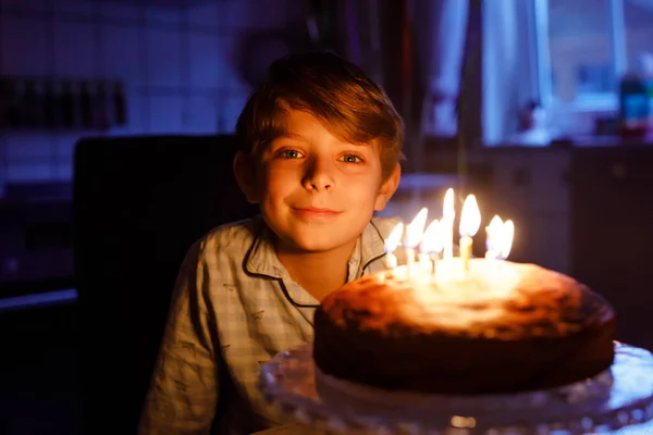 可爱的金发小男孩庆祝他的生日。孩子们在自家做的烤蛋糕上吹蜡烛，室内。学生生日聚会，家庭庆祝活动 — 图库照片