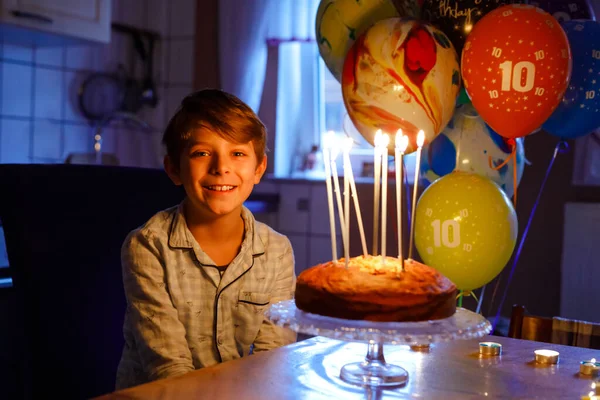 Sevimli, mutlu, küçük sarışın çocuk doğum gününü kutluyor. Çocuk ev yapımı kek üzerine mum üflüyor, kapalı alanda. Okul çocukları için doğum günü partisi, aile kutlaması — Stok fotoğraf