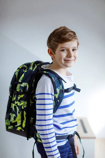 Menino bonito com mochila escolar em pé no quarto no início da manhã. Criança saudável feliz a caminho de aulas e escola. Conceito de educação — Fotografia de Stock