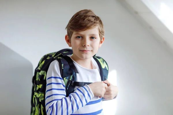 Menino bonito com mochila escolar em pé no quarto no início da manhã. Criança saudável feliz a caminho de aulas e escola. Conceito de educação — Fotografia de Stock