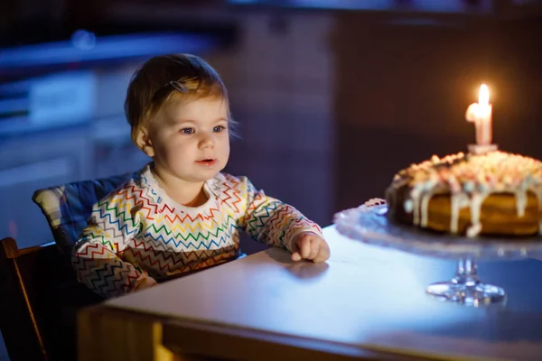 Schattig mooi klein meisje dat haar eerste verjaardag viert. Kind blaast een kaars op zelfgebakken taart, binnen. Verjaardags familiefeestje voor mooie peuter kind, mooie dochter — Stockfoto