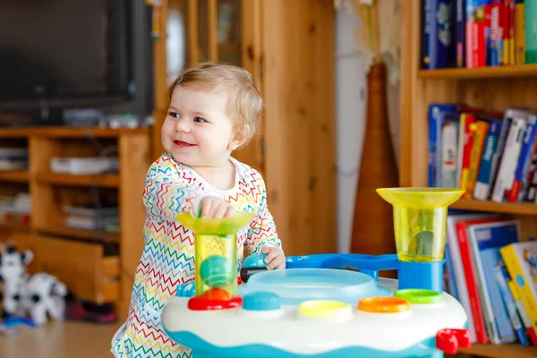 Feliz menina alegre brincando com diferentes brinquedos coloridos em casa. Adorável criança criança saudável se divertindo com brincar sozinho. Lazer ativo em ambientes fechados, creche ou escola infantil. — Fotografia de Stock