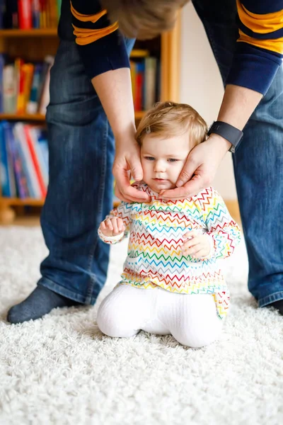 Adorable niña dando los primeros pasos. Padre enseñando a caminar a hija. Agarrándose de las manos — Foto de Stock