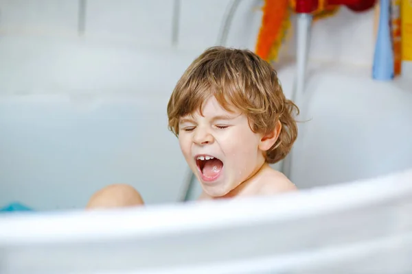 Carino bambino che gioca con l'acqua facendo il bagno nella vasca da bagno a casa. Adorabile felice bambino in buona salute prescolastico divertirsi, lavare i capelli e la testa e spruzzare con sapone — Foto Stock