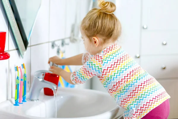 Gadis kecil yang lucu mencuci tangan dengan sabun dan air di kamar mandi. Anak manis belajar membersihkan bagian tubuh. Tindakan rutin kebersihan selama desease virus. anak di rumah atau pembibitan. — Stok Foto