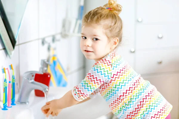 Carino piccolo bambino ragazza lavarsi le mani con acqua e sapone in bagno. Adorabile bambino che impara a pulire parti del corpo. Azione di routine igienica durante la malattia virale. bambino a casa o vivaio. — Foto Stock