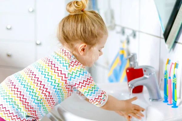 可爱的小女孩在浴室里用肥皂和水洗手。可爱的孩子学习清洁身体的部分。病毒性失调症期间的日常卫生行动.小孩在家或托儿所. — 图库照片