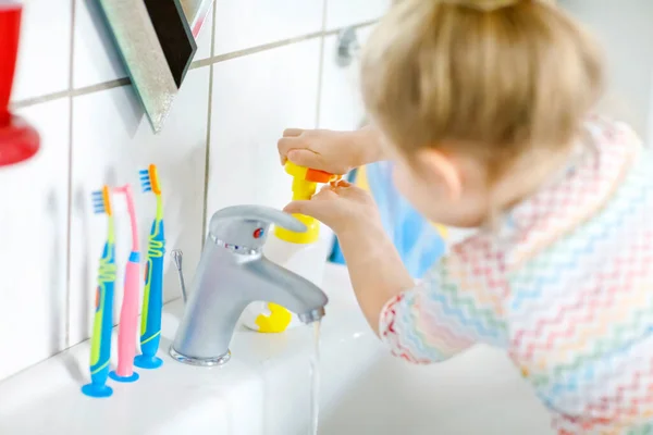 Słodka dziewczynka myje ręce mydłem i wodą w łazience. Urocze dziecko uczy się czyścić części ciała. Rutynowe działania higieniczne podczas choroby wirusowej. dziecko w domu lub przedszkolu. — Zdjęcie stockowe