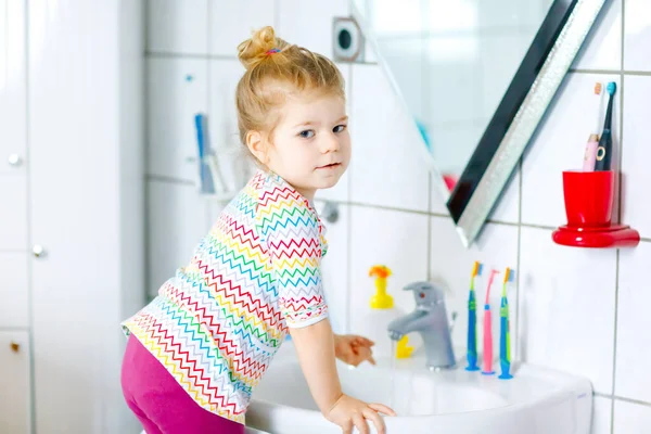 Mignon petit tout-petit fille se laver les mains avec du savon et de l'eau dans la salle de bain. Adorable enfant apprenant à nettoyer les parties du corps. Hygiène action de routine pendant la maladie virale. enfant à la maison ou à la crèche. — Photo