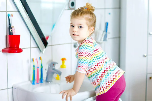 Schattig klein peuter meisje wassen handen met zeep en water in de badkamer. Schattig kind leren schoonmaken lichaamsdelen. Hygiëne routine actie tijdens virale desease. kind thuis of in de kinderkamer. — Stockfoto