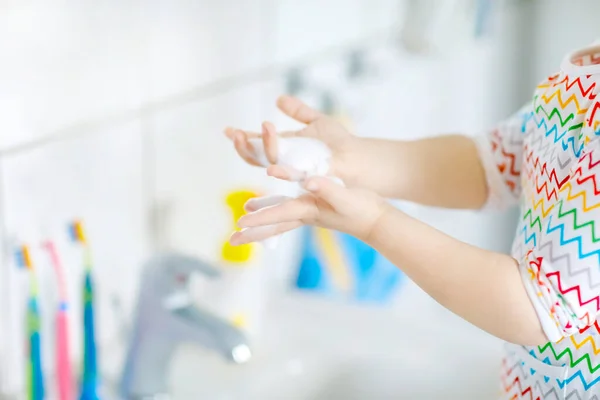 Close-up de menina pequena criança lavar as mãos com sabão e água no banheiro. Fechar crianças aprendendo a limpar partes do corpo. Ação de rotina de higiene durante a doença viral. criança em casa ou berçário. — Fotografia de Stock
