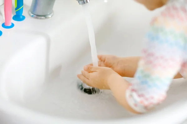 Close-up van kleine peuter meisje wassen handen met zeep en water in de badkamer. Close-up kind leren schoonmaken lichaamsdelen. Hygiëne routine actie tijdens virale desease. kind thuis of in de kinderkamer. — Stockfoto