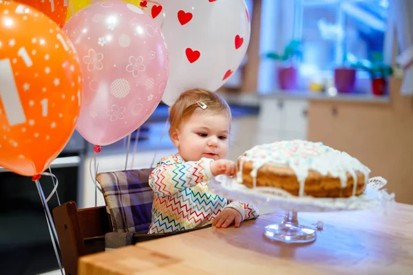 Adorable petite fille qui fête son premier anniversaire. Bébé manger des marshmellows décoration sur gâteau fait maison, intérieur. Fête d'anniversaire pour mignon tout-petit enfant, belle fille — Photo