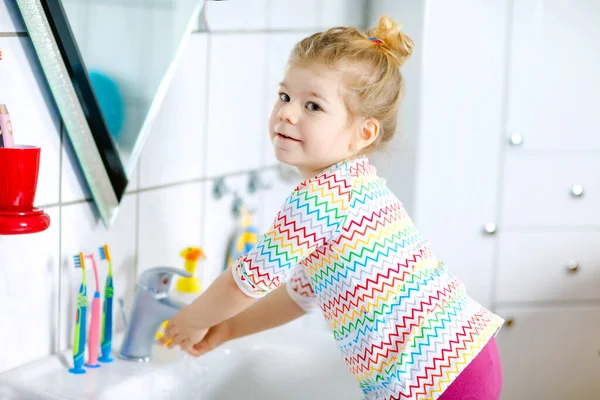 Mignon petit tout-petit fille se laver les mains avec du savon et de l'eau dans la salle de bain. Adorable enfant apprenant à nettoyer les parties du corps. Hygiène action de routine pendant la maladie virale. enfant à la maison ou à la crèche. — Photo