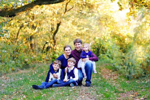 Porträtt av unga föräldrar med tre barn. Mor, far, två barn bröder pojkar och liten söt småbarn syster flicka har roligt tillsammans i höstskogen. Lycklig familj på fem — Stockfoto