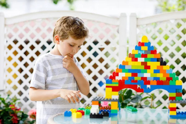 Pequena criança loira e garoto brincando com muitos blocos de plástico coloridos. — Fotografia de Stock