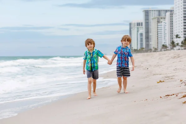 Due ragazzini che corrono sulla spiaggia dell'oceano — Foto Stock