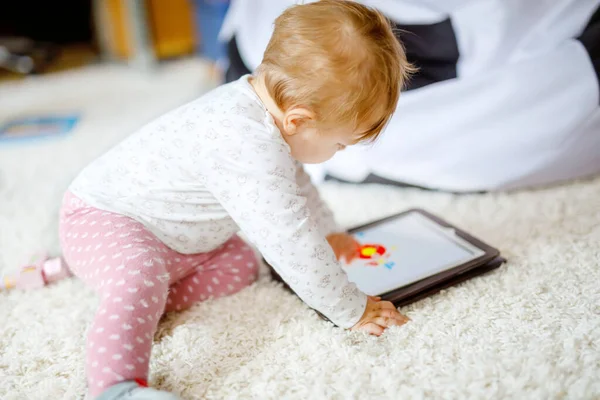 Bonito adorável bebê menina assistindo desenhos animados no tablet pc. Todder criança em casa tocando na tela e jogando jogos educativos no computador . — Fotografia de Stock