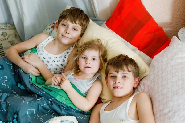 Tres niños en cuarentena contra el coronovirus jugando juntos en casa. Dos chicos de la escuela y una niña divirtiéndose en el interior. Niños activos. Quédate en casa concepto . — Foto de Stock