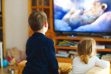 Sevimli küçük kız ve liseli çocuk TV 'de hayvan filmi ya da film izliyor. Mutlu sağlıklı çocuklar, Coronavirus karantinası sırasındaki kardeşler evde kalıyor. Erkek ve kız kardeş birlikte. Yüzü yok