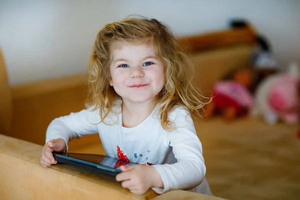 Schattig klein peuter meisje spelen met tablet pc thuis. Gezonde baby aanraken pad met vingers, op zoek cartoons en plezier hebben met educatieve games op de computer. betreffende quarantaine tegen het coronavirus — Stockfoto
