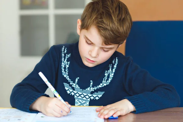 Hard-working happy school kid boy making homework during quarantine time from corona pandemic disease. Healthy child writing with pen, staying at home. Homeschooling concept — Stock Photo, Image
