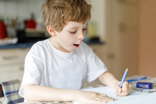 Çalışkan, mutlu okul çocuğu Corona salgınından dolayı karantina zamanında ödev yapıyor. Kalemle yazan sağlıklı bir çocuk, evde kalıyor. Evde eğitim kavramı — Stok fotoğraf