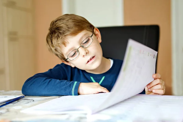 Un ragazzo della scuola felice che lavora sodo facendo i compiti durante la quarantena per una pandemia coronarica. Bambino sano che scrive con la penna, rimanendo a casa. Concetto di istruzione a casa — Foto Stock